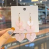 Jolies boucles d'oreilles pendantes en forme de cœur d'amour rose en acrylique.