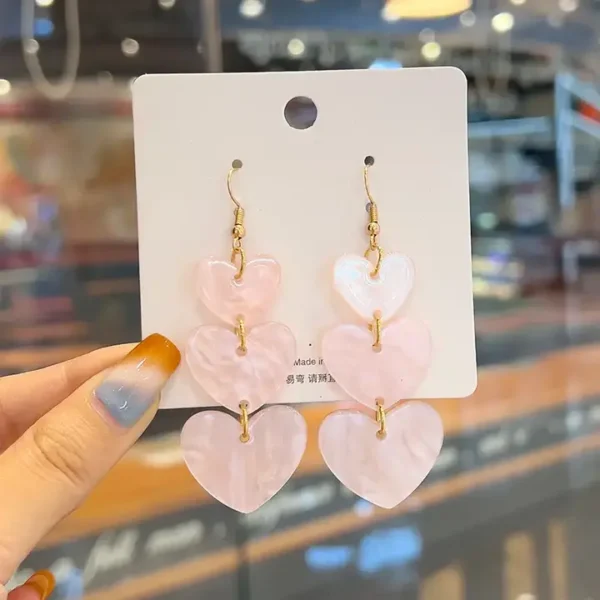 Jolies boucles d'oreilles pendantes en forme de cœur d'amour rose en acrylique.